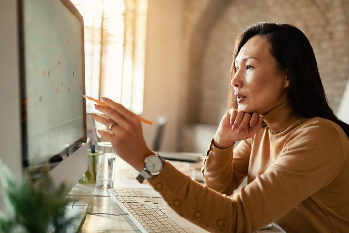 Asian female entrepreneur analyzing business progress on a computer in the office using competitive analysist tools.